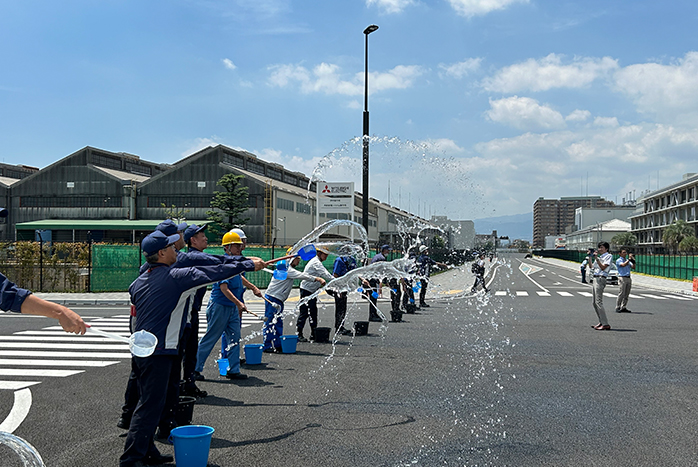 地区を通る道路の交差点で一斉に打ち水を実施